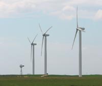 A traditional windmill, dwarfed by 220-foot tall generators