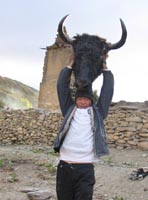 A boy raises a yak's head, fresh from the slaughter